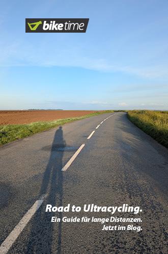 Ulreacycling – Ein Guide für Lange Distanzen. Jetzt im Blog. Der lange Schatten eines Radfahrer fällt in der Abendsonne auf eine Straße, die sich bis zum Horizont zieht.