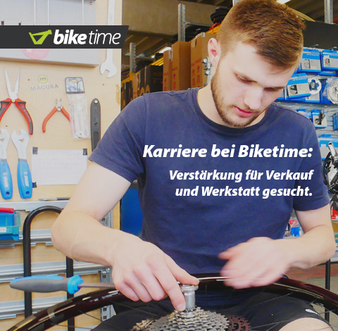 Auf dem Bild ist eine männliche Person zu erkennen, die an einem Laufrad schraubt. Im Hintergrund ist eine typische Fahrrad-Werkstatt erkennbar.