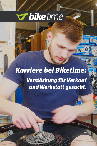 Auf dem Bild ist eine männliche Person zu erkennen, die an einem Laufrad schraubt. Im Hintergrund ist eine typische Fahrrad-Werkstatt erkennbar.