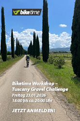 Auf einer langen, von Bäumen gesäumten Asphaltstraße ist ein Radfahrer zu erkennen. Die Landschaft drumherum sieht leicht hügelig aus.