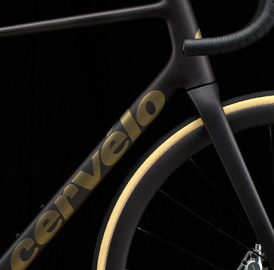 Das neue Cervelo R5: Gnadenlos leicht. Entwickelt für die steilsten Anstiege. Zu sehen ist ein Ausschnitt eines schwarzen Fahrradrahmens. Zu sehen sind Teile des Oberrohrs, des Unterrohrs, des Reifens, des Lenkers und der Gabel. Die Wortmarke „Cervelo” ist lesbar.