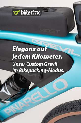 Zu erkennen ist ein Teil des türkisfarbenen Rahmens eines Gravel-Bikes. Am Rahmen sind mehrere Bikepacking-Taschen und eine Trinkflasche angebracht.