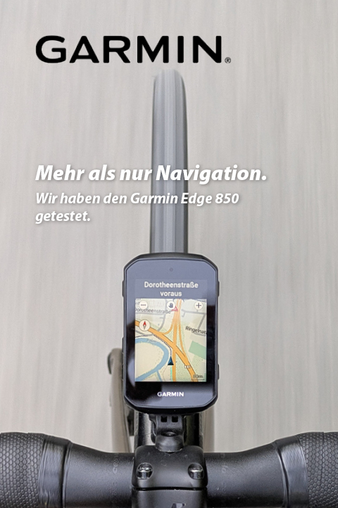 Zu erkennen ist ein Radcomputer, der auf einem Lenker eines Rennrads montiert ist. Das Bild zeigt den Radcomputer von oben, sodass auch die befahrene Straße sichtbar ist. Auf dem Radcomputer ist eine Kartennavigation sichtbar.