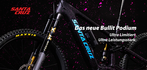 Das neue Bullit Podium: Ultra Limitiert. Ultra Leistungsstark. Zu erkennen ist der Ausschnitt eines schwarzen Fahrrads mit pinken Spritzern. Besonders prägnant ist die Gabel zu sehen - eine Podium-Gabel der Marke Fox. Es handelt sich um ein E-Mountainbike der Marke Santa Cruz - es ist das Bullit Podium.