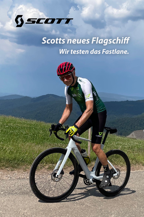 Scotts neues Flagschiff. Wir testen das Fastlane. Ein Radfahrer fährt auf einem weißen E-Rennrad einen Berg hoch. Im Hintergrund ist eine Berglandschaft zu erkennen.