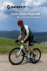 Scotts neues Flagschiff. Wir testen das Fastlane. Ein Radfahrer fährt auf einem weißen E-Rennrad einen Berg hoch. Im Hintergrund ist eine Berglandschaft zu erkennen.