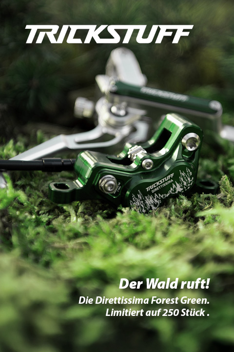 Ein grüner Bremssattel liegt im Moos. Der Bremssattel sieht sehr hochwertig aus und hat eine aufwendige Gravur, die einen Wald und die Wortmarke Trickstuff Direttissima zeigt.