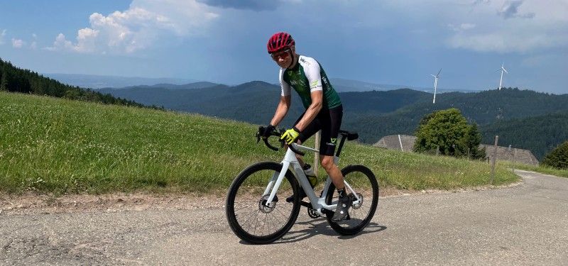 Ein Radfahrer fährt auf einem weißen E-Rennrad eine Rampe hoch und ist links im Bild zu sehen.