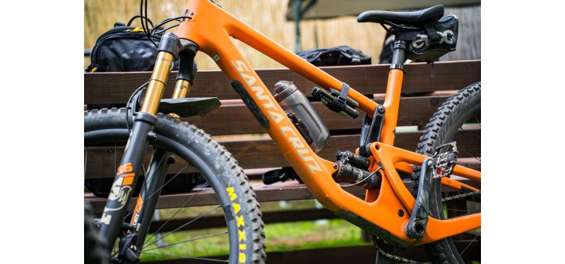 Ein orangenes Mountainbike von Santa Cruz lehnt an einer Parkbank.