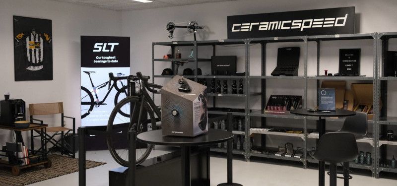 Edle Lagerhalle mit unterschiedlichen Bike-Komponenten und einem Fahrrad. Ein großes Schild der Firma Ceramicspeed ist zu erkennen.