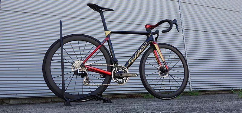 Ein schwarz-rot-goldenes Rennrad steht vor einer Lagerhalle.