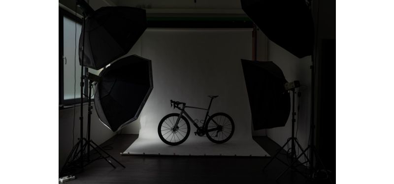 Die Umrisse eines Rennrads sind erkennbar. Es steht in einem abgedunkelten Fotostudio.