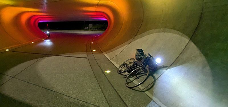 Ein Fahrrad liegt angelegt in einem beleuchteten Tunnel an der Wand.