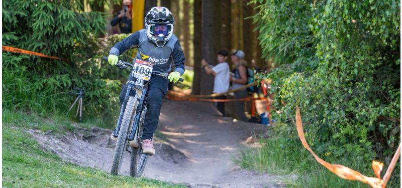 Ein Kind fährt auf einem Mountainbike einen Trail entlang.
