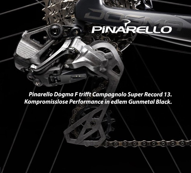 Ein Fahrrad-Schaltwerk in Metall-Schwarz im Fokus. Befestigt an einem teilweise sichtbaren Dogma-Rahmen. Fahrrad-Kassette und Kette sind auch teilweise sichtbar.