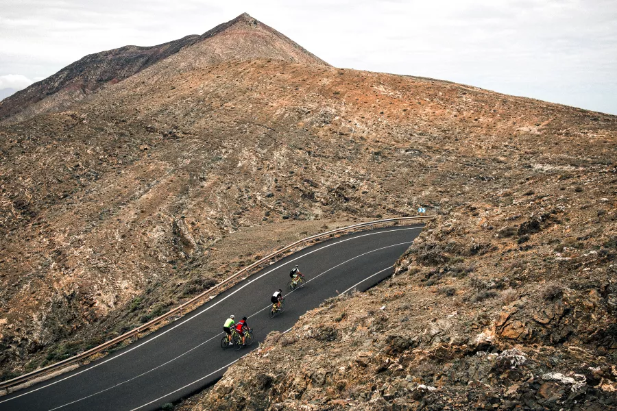 Ein Berg mit einer Straße und eine Gruppe BMC Teammachine SLRs kämpft sich den Weg hoch.